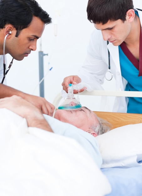 A doctor putting oxygen mask on a senior patient 