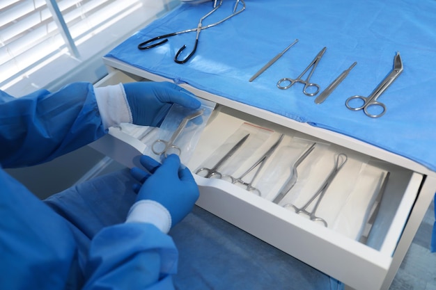 Doctor putting Pott39s scissors into drawer indoors closeup Table with different surgical instruments