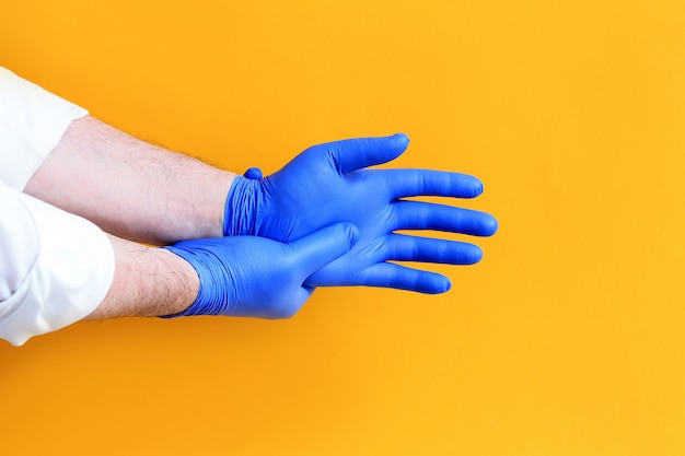 Photo doctor putting on protective blue gloves.