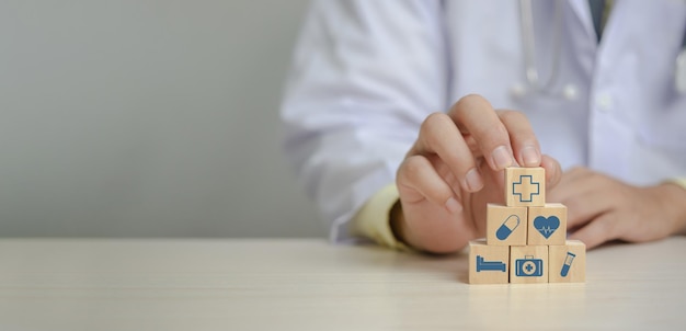 Doctor putting and stacking wooden block cube icon symbol medical health care on table panorama background concept