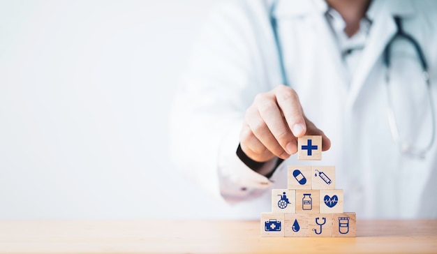 Foto medico che mette e impila il cubo di blocco di legno che stampa l'assistenza sanitaria dello schermo e le icone mediche per il concetto di salute e benessere.