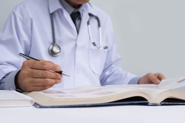 Doctor reading medical textbook on table