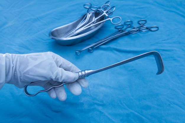 Photo doctor 's hand holding medical instrument (retractor) during surgical operation