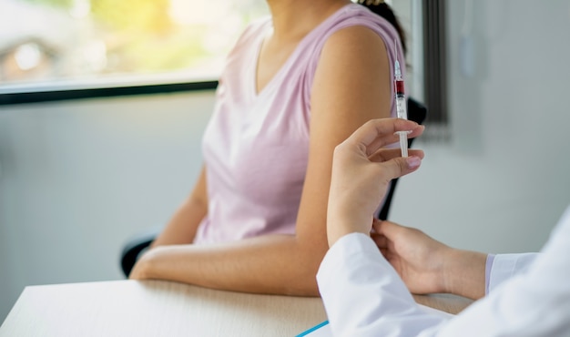 The doctor's hand holding a syringe and was about to vaccinate a patient