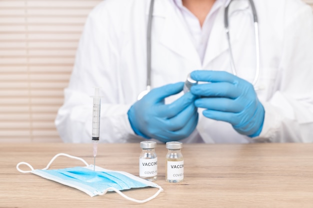 Doctor's hand holding vaccine vial on the doctor's desk