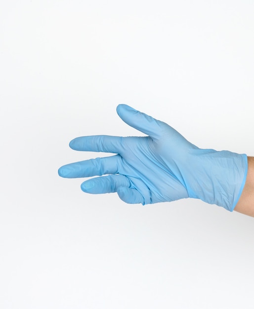 Фото Рука врача в синей медицинской перчатке держит объект на белом фоне. скопируйте пространство, удерживайте любой объект