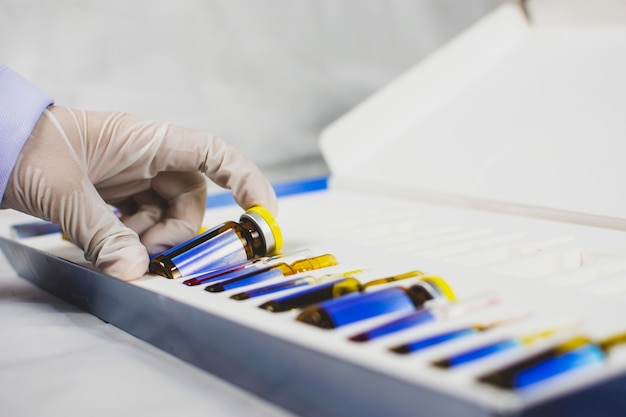 La mano del medico sta raccogliendo la bottiglia della fiala di medicina dal cofanetto.