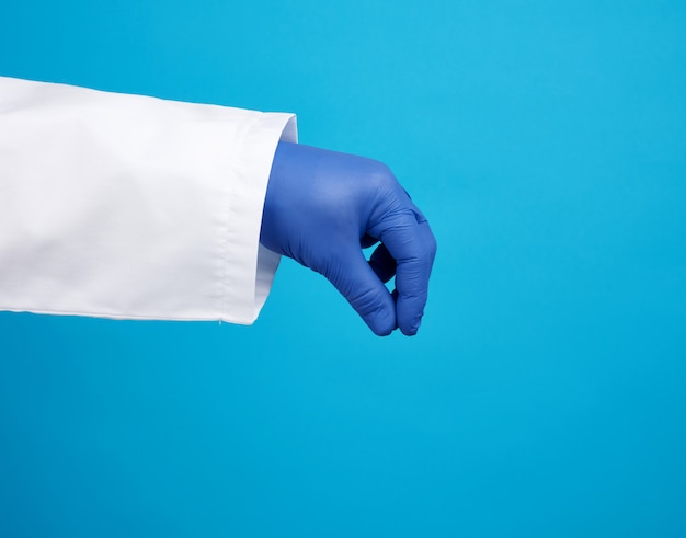 Photo doctor's hand is wearing a blue sterile rubber glove holding an object