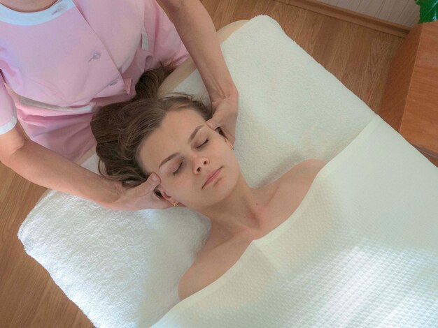 The doctor's hands are on the temples of a young woman Close-up facial massage