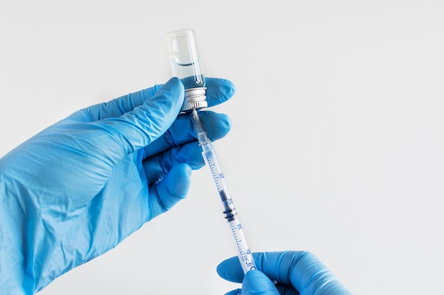 Doctor's hands in a blue gloves holding syringe and vaccine