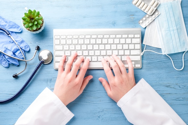 doctor's hands and computer on a blue table