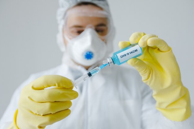 Doctor's hands fill syringe with coronavirus vaccine, preparing for injection. Covid-19 protection.