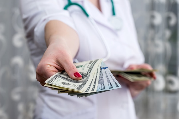 Doctor's hands giving dollar banknotes, close up