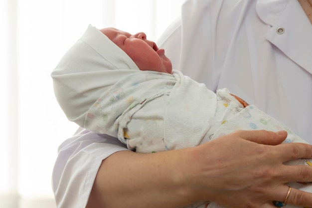 医師の手には、おむつに包まれた新生児が握られています。