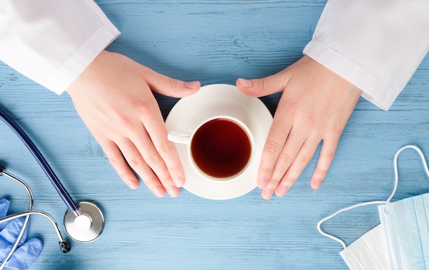 Doctor's hands with coffee at the table. Doctor's desk.