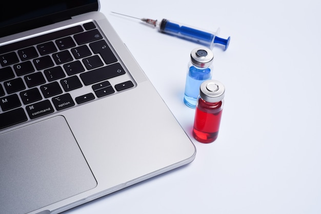 Doctor's office  with modern workplace in medical clinic. Laptop, medicine ampoules and notepad and syringe on the table top view.