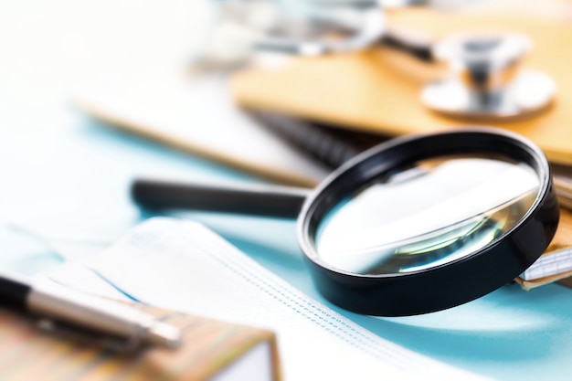 Doctor's workplace with magnifying glass, stethoscope or phonendoscope, notebooks and documents