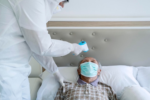 Doctor scanning his patients temperature on a bed