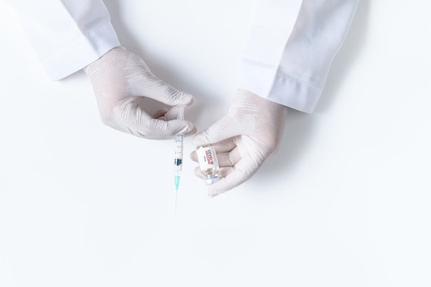 医師または科学者がインフルエンザ、はしか、コロナウイルスワクチンを保持している白い手袋を手に白い背景に病気の発生ワクチン接種、薬と薬の概念
