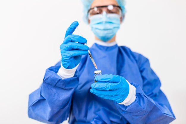 Doctor or scientist in PPE suite uniform holding medicine liquid vaccine