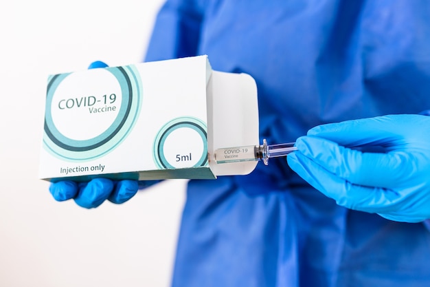 Doctor or scientist in PPE suite uniform holding medicine liquid vaccine