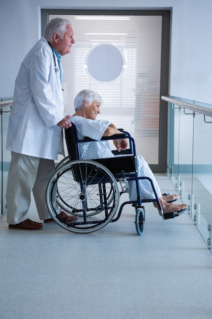 Doctor and senior patient on wheelchair in the passageway