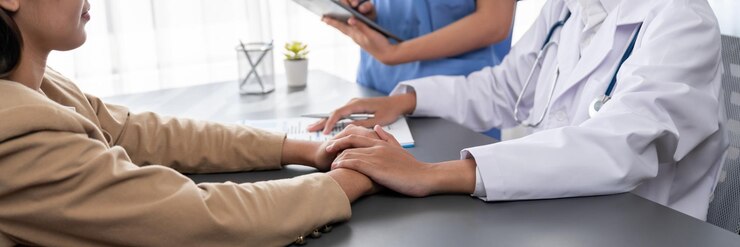 Photo 의사는 의학적 진단 보고서를 보여주고 어린 환자의 손을 잡고 동정심이 넘치는 의료 상담을 제공하여 의사의 클리닉 사무실에서 지원적이고 전문적입니다.