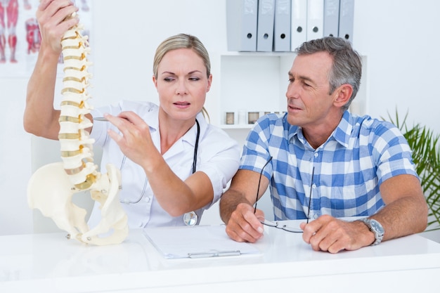 Doctor showing anatomical spine to her patient 