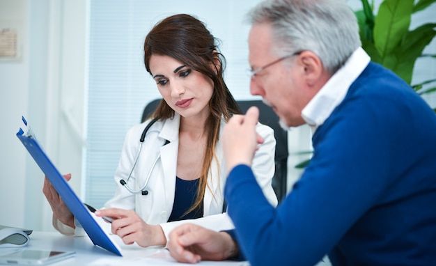 Doctor showing a medical document to a senior patient. Focus on the woman