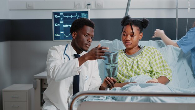 Photo doctor showing medical x-ray to patient at hospital