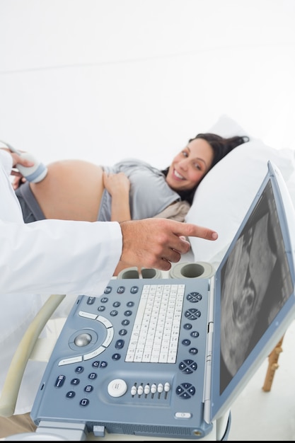 Doctor showing ultrasound monitor to pregnant woman 