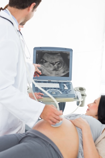 妊娠中の女性に超音波結果を示す医師