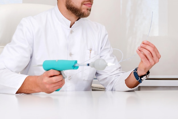 Doctor showing varicose veins removal device. Surgeon man phlebologist working in moder clinic. Medical tools in hospital. Varicose veins treatment.