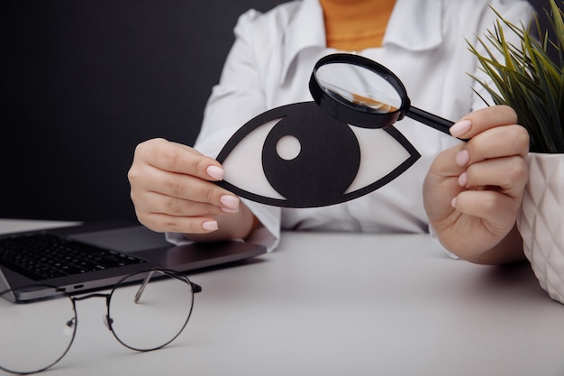 Doctor showing a wooden eye by magnifier