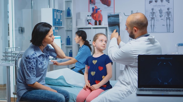 Photo doctor showing x-ray image of a bone to patient. healthcare practitioner physician specialist in medicine providing health care services consultation, radiographic treatment in clinic cabinet hospital