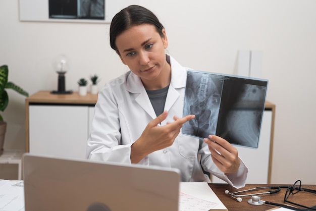 Photo doctor shows image of xray examination explaining features of disease to patient online on laptop