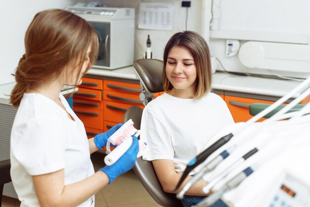 doctor shows the patient how to properly brush her teeth with an electric toothbrush