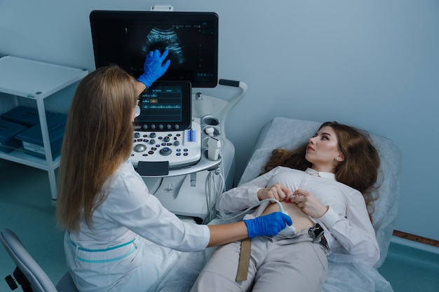 The doctor shows the patient on the screen of a modern ultrasound machine during an examination at the clinic