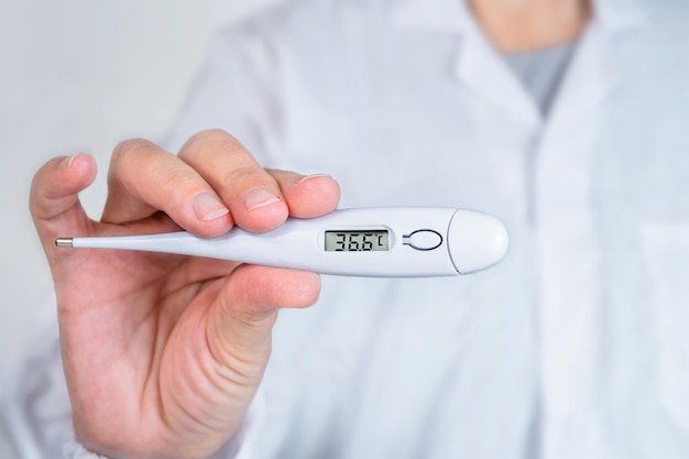 Doctor shows a thermometer with normal temperature close up