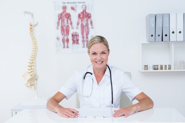 Doctor sitting at her desk smiling at camera 