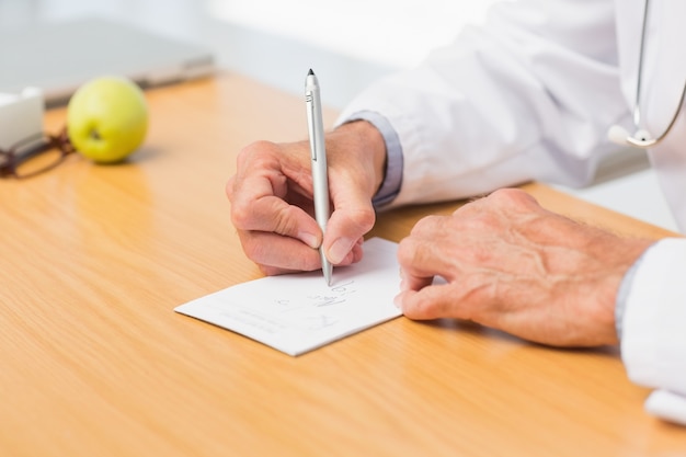 Doctor sitting at his desk writing out a prescription