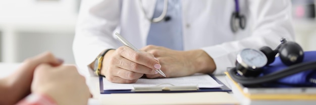 Doctor sitting at table and preparing medical records with ballpoint pen closeup health