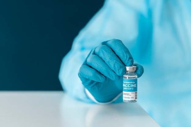 Photo doctor in special equipment holding the covid 19 vaccine