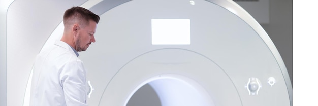 클리닉의 현대적인 검사 방법에서 MRI 기계에 누워 있는 환자 근처에 서 있는 의사