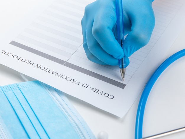 Doctor in sterile gloves filling vaccination protocol