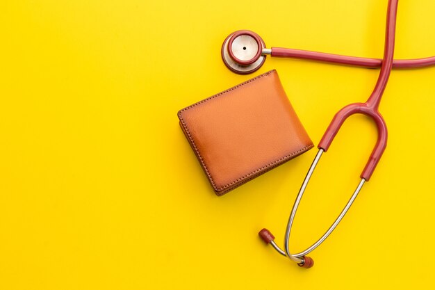 Doctor stethoscope and the new leather brown men wallet on yellow. Budget for health check or money and financial concept