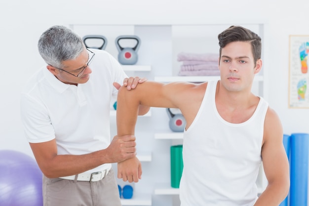 Doctor stretching a young man arm