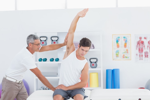 Doctor stretching a young man arm