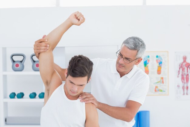 Doctor stretching a young man arm