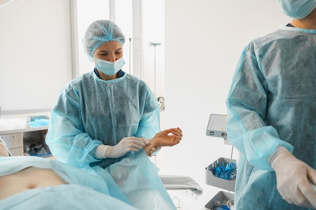 Врач-хирург проверяет пульс пациента во время операции в операционной